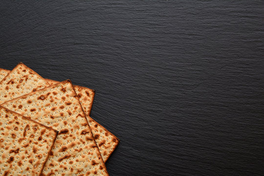 Slices of matzo on plate, board, tray of black slate. Fresh Easter bread made from wheat flour in the form of very thin dry cakes.