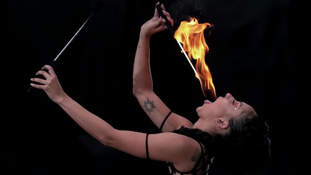 Fire artist entertainer breathes burning flame in the dark