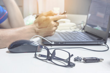 Side view shot of a man's hands using smart phone with notebook glasses and flash drive