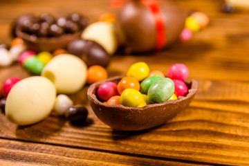 Chocolate easter eggs and multicolored candies on wooden table