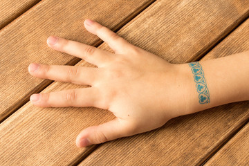 Palm of little girl with baby tattoo on wooden background