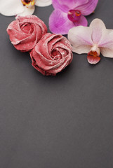 Fototapeta na wymiar Sweet Pink Meringues on Blue Gray background with Orchid Flowers. Spring Background. Copy space. Breakfast.