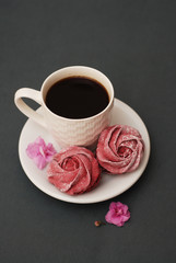 Sweet Pink Meringues and Cup of Coffee on Blue Gray background with Pink Flowers. Spring Background with copy space. Breakfast.