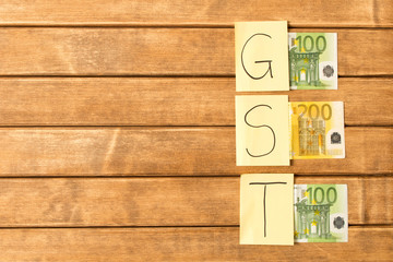 Goods and Services Tax . GST inscription with banknotes on wooden background