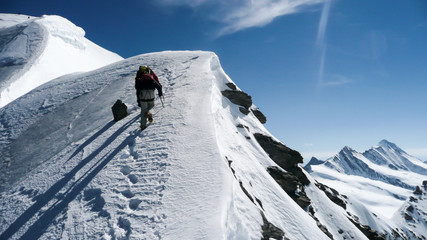 mountain guide and client on a steep north face slope heading towards the summit with a great view of the surrounding mountain landscape in the Alps near Grindelwald
