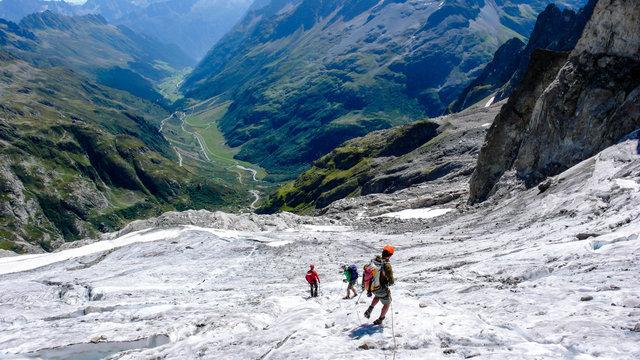 group of male mountain climbers crossing a glacier on their way down from a high alpine peak