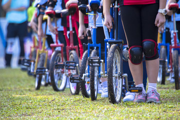 Colorful unicycles lined up in straight line awaiting respective turn for relay.