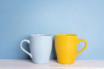 Blue and yellow mugs on a blue background with copy space.