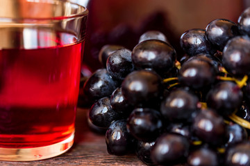 Red grape juice in glass and grapes close