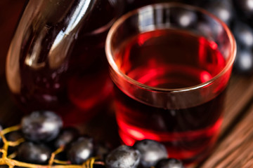 Red grape juice in glass and grapes close