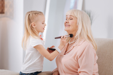 Forever beautiful. Nice little girl holding a brush while powdering her grannys neck