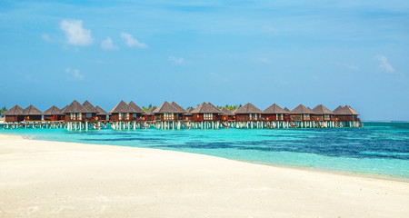 Wooden bungalow on the background of azure water and blue sky, Maldives