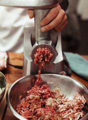 Close up of front part of meat grinder or mincing-machine with mincemeat in. Showing the forcemeat process.