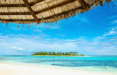 Fototapeta na wymiar Exotic uninhabited island with a sandy beach and tall palm trees with a palm tree umbrella