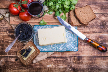 Natural food and ingredients, breakfast with butter, bread and black caviar on wooden background
