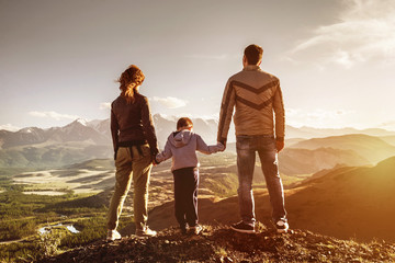 Family with son stands mountains sunset