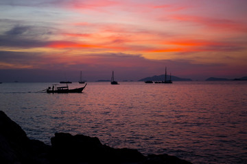 Silhouette Longtail boat with coastal fishing village,Beautiful scenery view in sunset twilight time.
