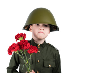 sad boy in military uniform and iron helmet holds flowers, isolated on white