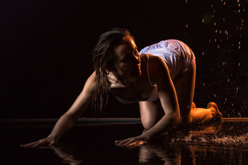 Fototapeta na wymiar Girl in white dress in water in a dark water in pool in studio and dark background