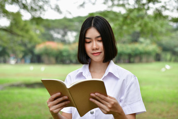 Obraz premium Education Concepts. Beautiful student reading books in the park. Beautiful girl are relaxing in the park. Young student are happy to read. Young student love to study. Education of Asian Women.