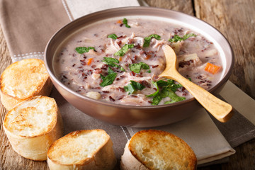 Natural food: wild rice soup with chicken and vegetables close-up on a plate and toast. horizontal