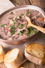 soup of wild rice with chicken and vegetables close-up in a bowl and toast. vertical