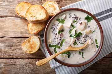 Hot soup of wild rice with mushrooms and vegetables close-up and toast. horizontal top view