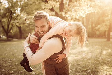 Smiling father in autumn day with daughter.