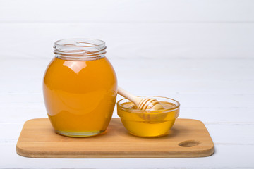 Honey with wooden honey dipper on wooden table