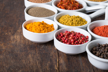 colorful spices in ceramic containers on a dark background