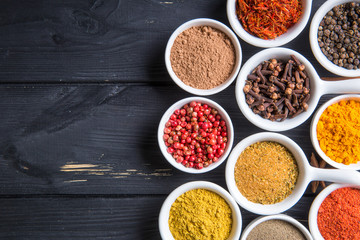 colorful spices in ceramic containers on a dark background