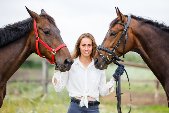 Young rider girl having fun with two her horses. Equestrian sport concept background