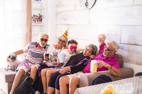 family and friends and dog at home doing party celebration after lunch. bright image for fun and smile concept. from grandfather to young teenager mixed generations
