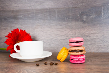 coffee cup and colorful macaroons on wooden table