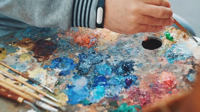 Artist mixes paints on the palette before painting a picture