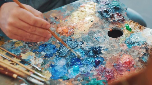 Artist mixes paints on the palette before painting a picture