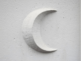 crescent moon on a white stone wall