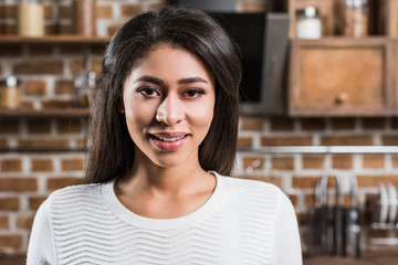 portrait of beautiful young african american woman smiling at camera in kitchen