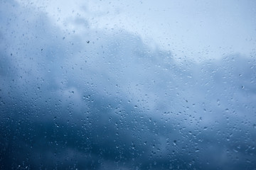 rain drops on glass blue clouds rainy mood, down with cold,