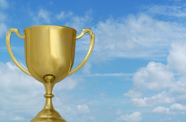 Gold winner cup on blue sky with white clouds background