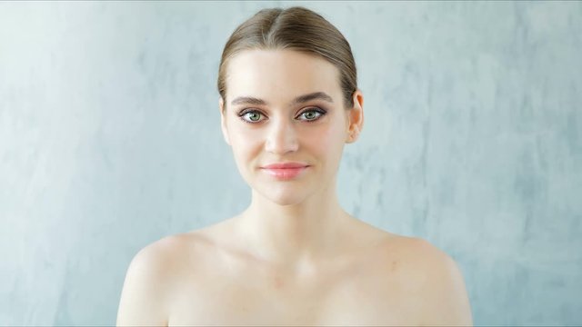 Beautiful young woman with perfect fresh skin looking at camera. Skincare concept