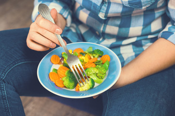 The girl holds a plate with vegetables. Healthy eating concept. A girl in jeans and a plaid shirt. Casual Style. Proper nutrition. Diet. Health. Vegetarian food. Vegans food. Toned image.