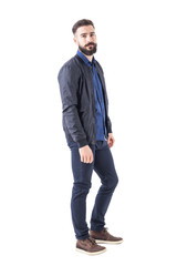 Side view of confident relaxed macho guy in bomber jacket posing and looking at camera. Full body isolated on white background. 
