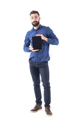 Friendly smiling bearded business man holding tablet in both hands and showing it at camera. Full body isolated on white background. 