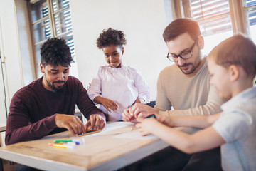 Two fathers play educational games with their children, having fun.