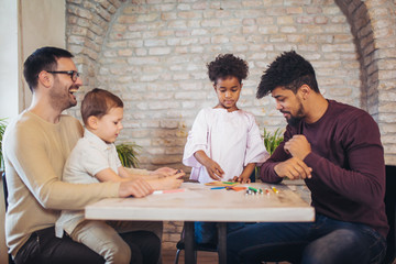 Two fathers play educational games with their children, having fun.