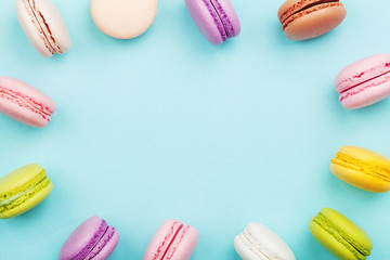 Cake macaron or macaroon on turquoise pastel background from above. Colorful cookies on dessert top view.