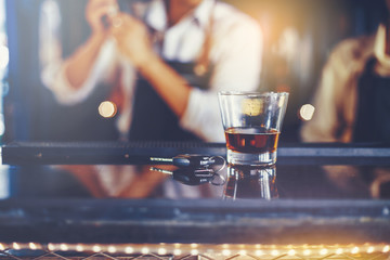 Glasses of liquor and alcohol are placed beside the car keys at the bar and bartender as background. Selected focus. Drink Don’t Drive concept