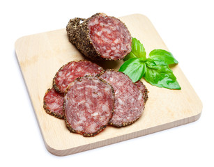 Dried organic salami sausage covered with pepper on wooden serving board