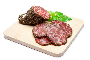 Dried organic salami sausage covered with pepper on wooden serving board